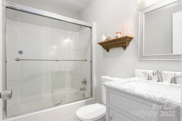 bathroom with bath / shower combo with glass door, toilet, and vanity