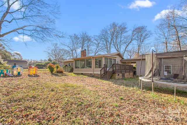 back of property with a playground, a trampoline, a sunroom, and a chimney