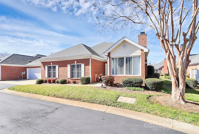 view of front of property featuring brick siding, an attached garage, a front lawn, a chimney, and driveway