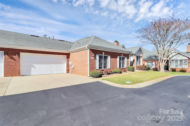 view of front of house with a front lawn, concrete driveway, a garage, brick siding, and a chimney