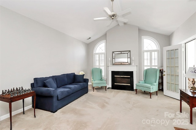 living area with visible vents, carpet floors, a fireplace with flush hearth, ceiling fan, and vaulted ceiling