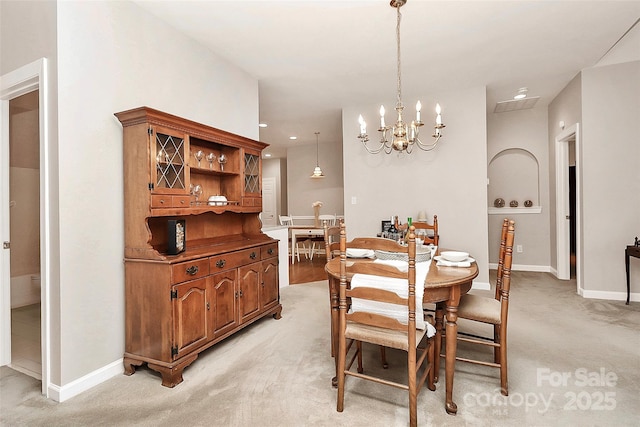 dining area featuring light carpet, baseboards, and a chandelier