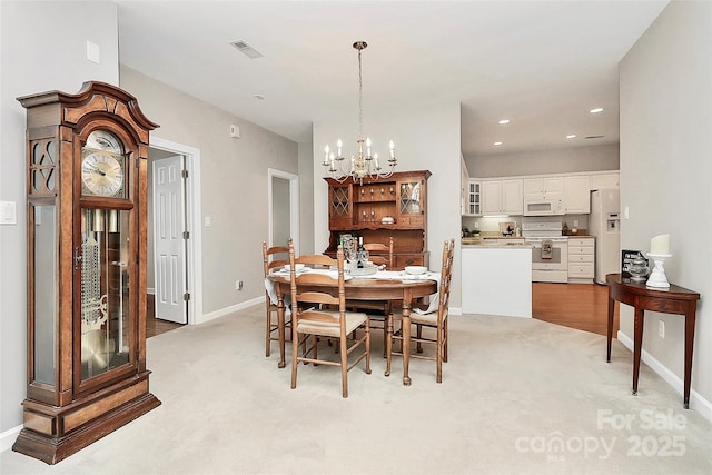 dining space with an inviting chandelier, recessed lighting, light colored carpet, and baseboards