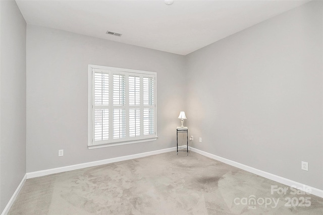 carpeted spare room featuring baseboards and visible vents