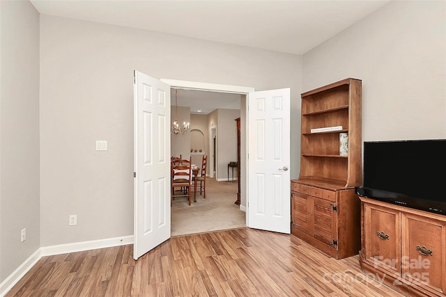 living area with light wood-style flooring, a notable chandelier, and baseboards