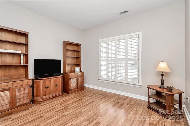 living area with light wood finished floors, visible vents, and baseboards