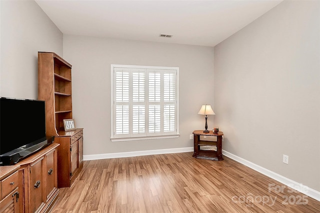 living area featuring visible vents, light wood-style flooring, and baseboards