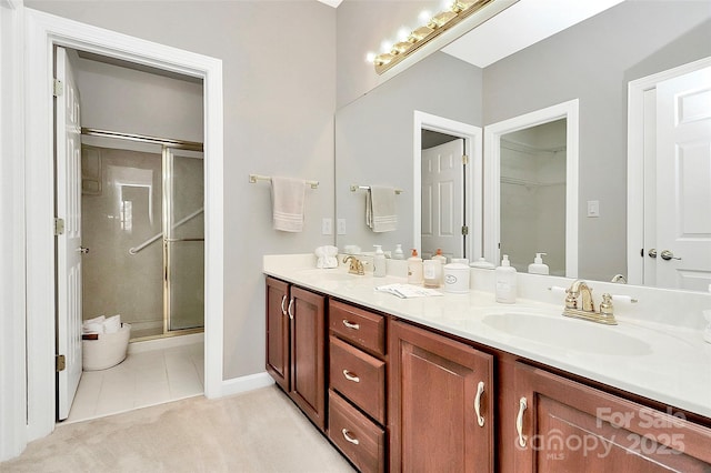 bathroom with a sink, double vanity, a shower stall, and tile patterned flooring