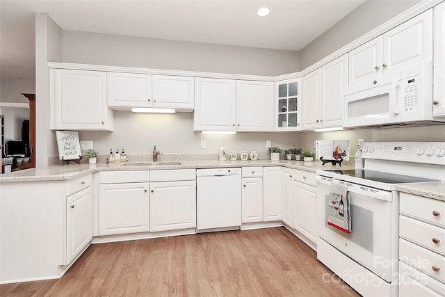 kitchen with white appliances, light wood-style flooring, and white cabinets