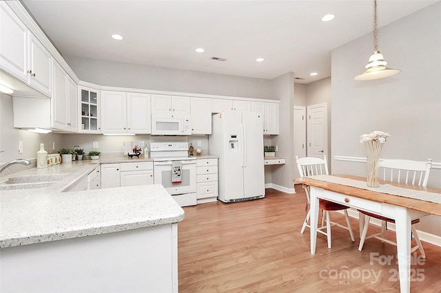 kitchen with visible vents, light wood-style flooring, white cabinets, white appliances, and a sink