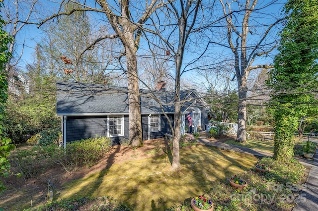 view of front of home with a shingled roof and a chimney