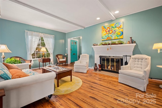 living room with beam ceiling, a brick fireplace, baseboards, and wood finished floors