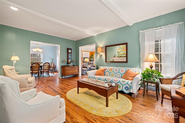 living room with a chandelier, beamed ceiling, and wood finished floors