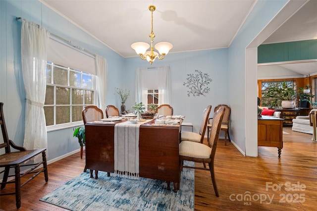 dining space featuring baseboards, wood finished floors, a chandelier, and ornamental molding