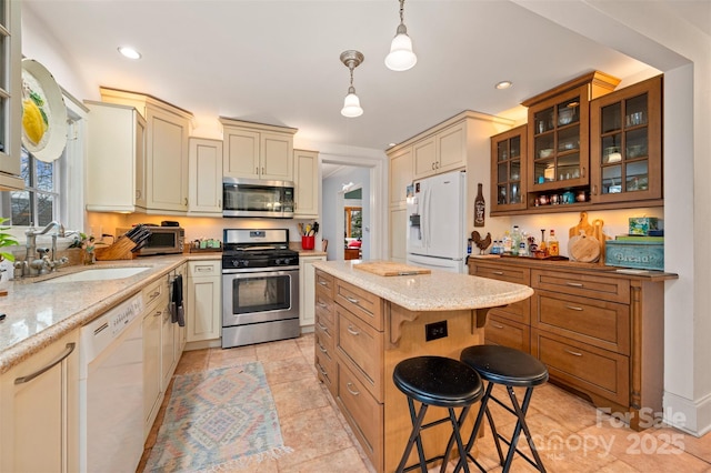 kitchen featuring a center island, light stone counters, appliances with stainless steel finishes, a kitchen breakfast bar, and a sink