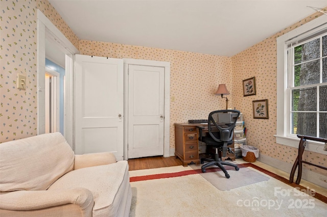 home office featuring wallpapered walls, wood finished floors, and baseboards