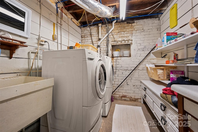 washroom with washer and dryer, brick wall, and a sink