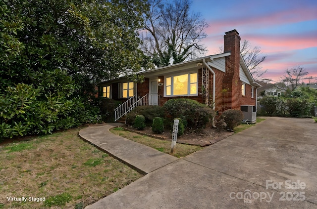 ranch-style home featuring brick siding, driveway, and a chimney