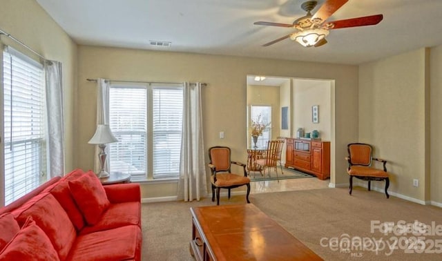 living area with carpet, a ceiling fan, visible vents, and baseboards