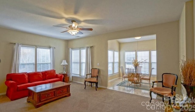 living area with a wealth of natural light, baseboards, and a ceiling fan