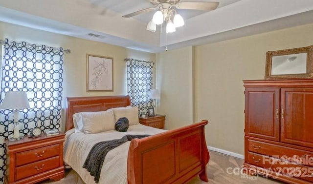 bedroom featuring a ceiling fan, a tray ceiling, baseboards, and visible vents