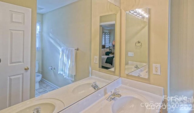 bathroom featuring double vanity, toilet, and a sink