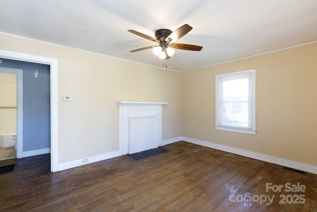 spare room featuring a ceiling fan, visible vents, dark wood-style flooring, and baseboards