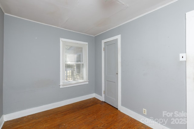 spare room with ornamental molding, baseboards, and wood finished floors