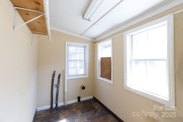 laundry area featuring laundry area, stone finish floor, and baseboards