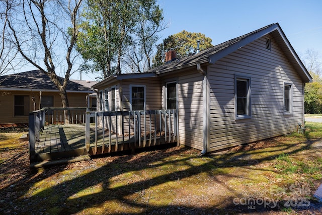 view of home's exterior with a deck, a yard, and a chimney