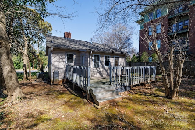 back of property with a wooden deck, central air condition unit, a chimney, and fence