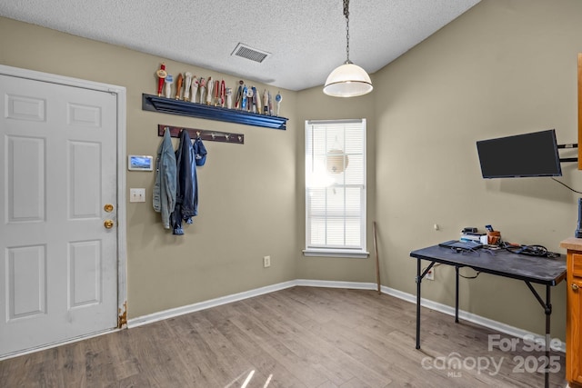 interior space featuring visible vents, a textured ceiling, baseboards, and wood finished floors