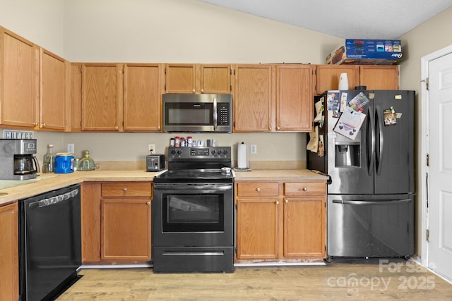 kitchen with black appliances, light countertops, lofted ceiling, light wood-style flooring, and a textured ceiling