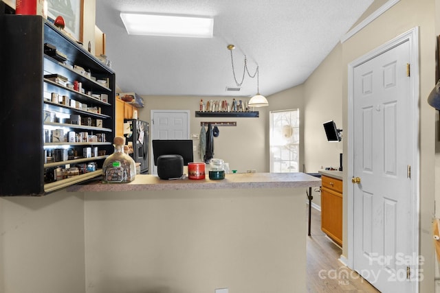 kitchen with light wood finished floors, visible vents, stainless steel fridge, a textured ceiling, and open shelves