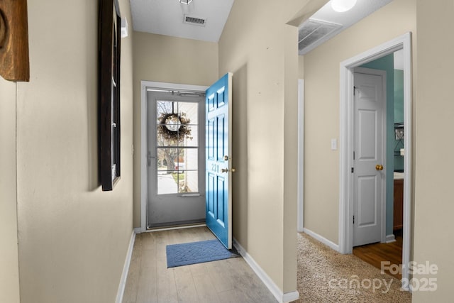 foyer entrance featuring baseboards, visible vents, and light wood-type flooring