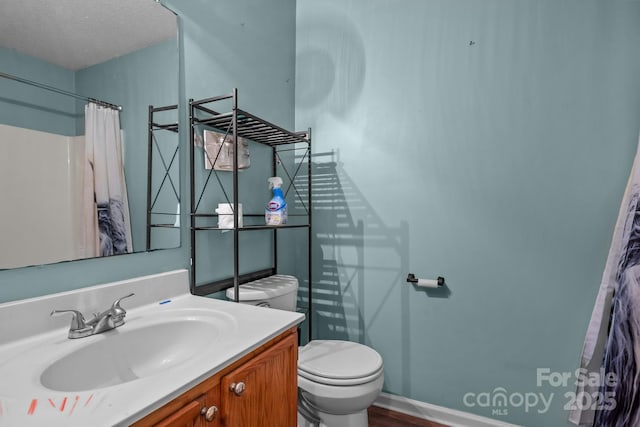 full bathroom featuring vanity, a shower with shower curtain, baseboards, a textured ceiling, and toilet