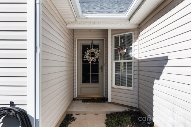 doorway to property with roof with shingles