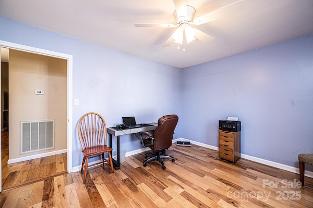 office space with visible vents, baseboards, a ceiling fan, and light wood finished floors