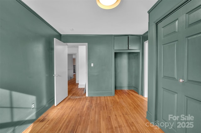 unfurnished bedroom featuring baseboards, a closet, and light wood-type flooring