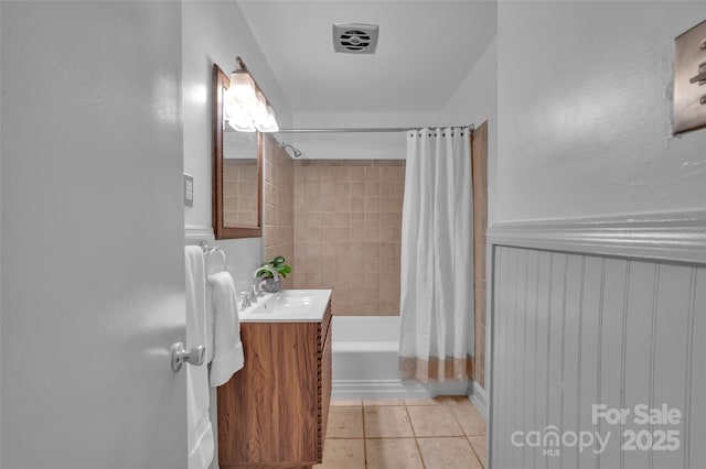 bathroom featuring tile patterned floors, shower / bath combo with shower curtain, vanity, and wainscoting