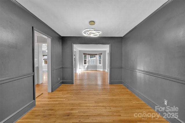 corridor featuring an inviting chandelier and light wood finished floors