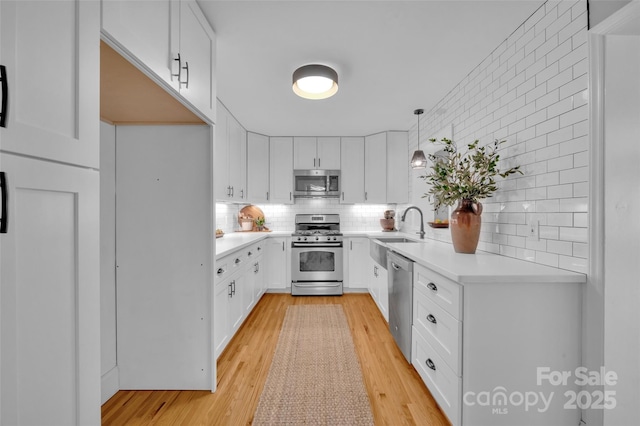 kitchen featuring stainless steel appliances, light wood-style floors, decorative backsplash, and light countertops