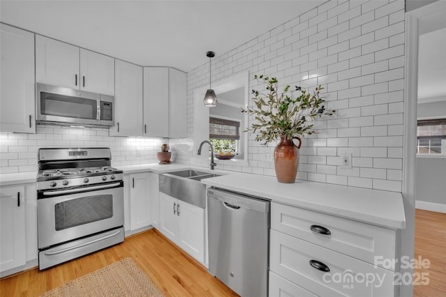 kitchen with a sink, stainless steel appliances, light countertops, and light wood finished floors