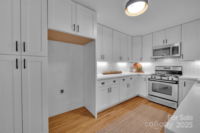 kitchen featuring appliances with stainless steel finishes, light wood-style flooring, white cabinets, and light countertops