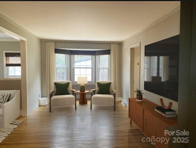 living area with a healthy amount of sunlight, crown molding, and wood finished floors