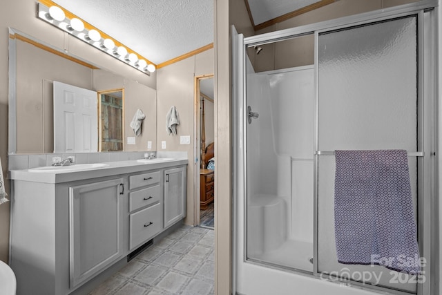 full bath featuring double vanity, tile patterned floors, an enclosed shower, a textured ceiling, and a sink