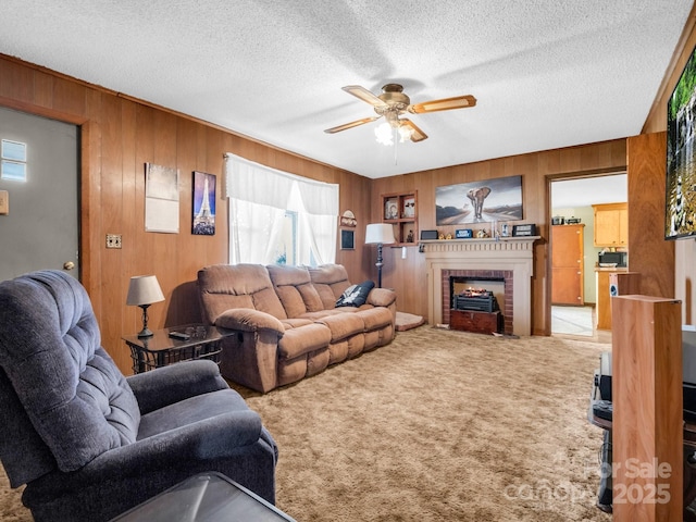 living room featuring carpet, a ceiling fan, wood walls, and a textured ceiling