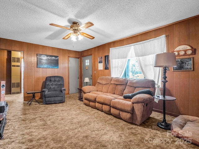 carpeted living room featuring a textured ceiling, wood walls, and ceiling fan