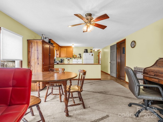 carpeted dining room with baseboards, a textured ceiling, and ceiling fan