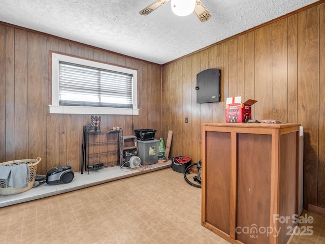 misc room featuring tile patterned floors, wooden walls, a textured ceiling, and a ceiling fan